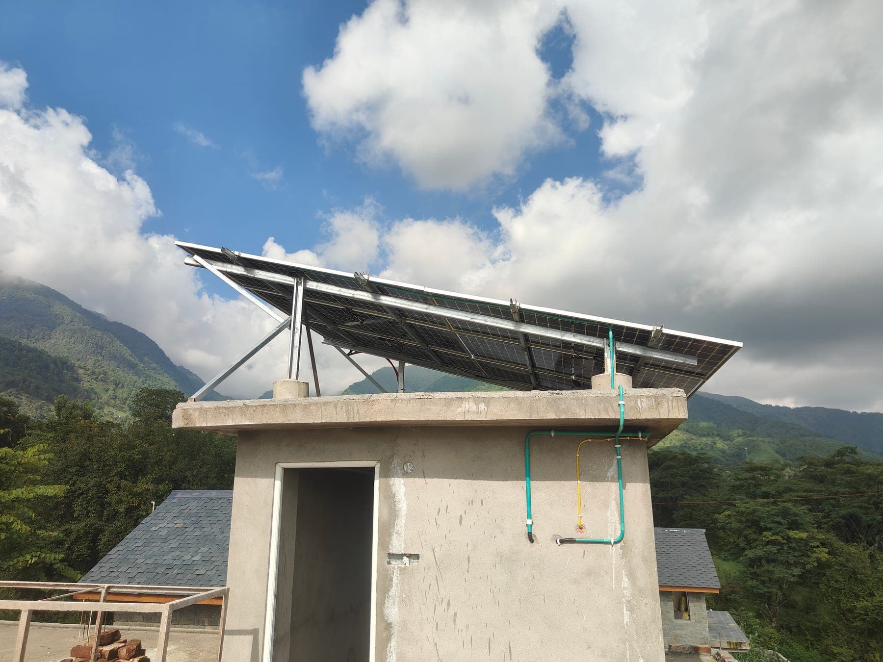 Rooftop solar panels against the Dhauladhar mountains — the property's solar power setup.