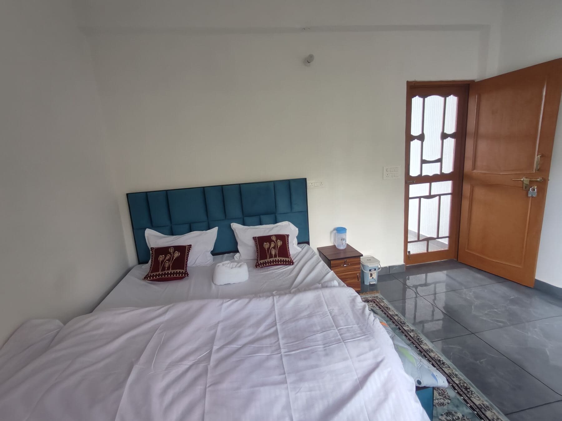 A well-lit bedroom with a teal headboard, one of the upper-floor rooms.